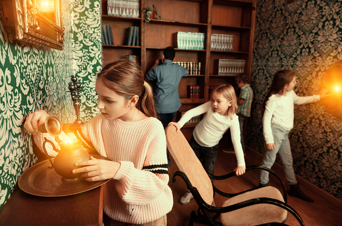Group of young friends trying to find solution of quest in escape room with antique furnitures